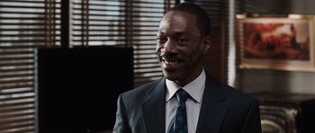 Movie still from “Imagine That” (2009), directed by Karey Kirkpatrick – A man in a suit and tie smiling for the camera; Close Up shot, Over the shoulder angle