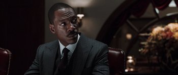 Movie still from “Imagine That” (2009), directed by Karey Kirkpatrick – A man in a suit sitting in a chair; Close Up shot, Low angle