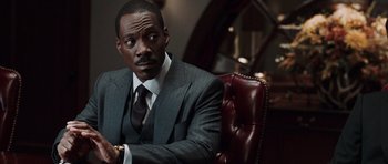 Movie still from “Imagine That” (2009), directed by Karey Kirkpatrick – A man in a suit and tie sitting in a chair; Close Up shot, Over the shoulder angle