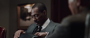 Movie still from “Imagine That” (2009), directed by Karey Kirkpatrick – A man in a suit and tie fixing his tie; Close Up shot, Over the shoulder angle
