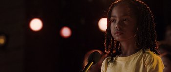 Movie still from “Imagine That” (2009), directed by Karey Kirkpatrick – A young girl is speaking at a microphone; Close Up shot, Over the shoulder angle