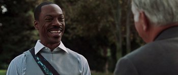 Movie still from “Imagine That” (2009), directed by Karey Kirkpatrick – A man in a dress shirt and tie smiling for the camera; Close Up shot, Over the shoulder angle
