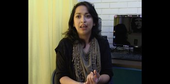 Movie still from “In Broad Daylight: The Narvarte Case” (2022), directed by Alberto Saúl Arnaut Estrada – A woman sitting in front of a tv in front of a brick wall; Close Up shot, Low angle