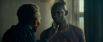 A man talking on a phone while a woman holds his hand up to his ear