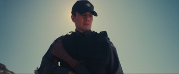 Movie still from “Inception” (2010), directed by Christopher Nolan – A man in a uniform holding a rifle; Medium shot, Low angle