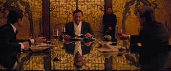 Movie still from “Inception” (2010), directed by Christopher Nolan – A man sitting at a table with a plate in front of him; Medium shot, Over the shoulder angle