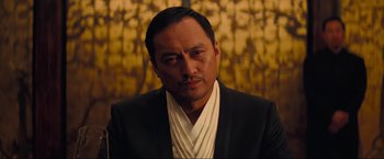 Movie still from “Inception” (2010), directed by Christopher Nolan – A person wearing a suit and tie; Close Up shot, Over the shoulder angle