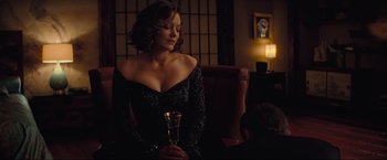 Movie still from “Inception” (2010), directed by Christopher Nolan – A woman sitting in a chair holding a glass of wine; Medium shot, Over the shoulder angle