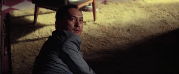 Movie still from “Inception” (2010), directed by Christopher Nolan – A man sitting on the ground in a room; Close Up shot, Low angle