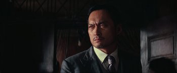 Movie still from “Inception” (2010), directed by Christopher Nolan – A person wearing a suit and tie; Close Up shot, Low angle