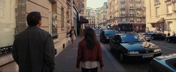 Movie still from “Inception” (2010), directed by Christopher Nolan – A woman walking down a street past a building; Wide shot, Over the shoulder angle