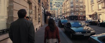 Movie still from “Inception” (2010), directed by Christopher Nolan – A woman is walking down the street in a red jacket; Wide shot, Over the shoulder angle