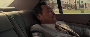 Movie still from “Inception” (2010), directed by Christopher Nolan – A man in a suit sleeping in the back of a car; Close Up shot, Low angle