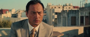 Movie still from “Inception” (2010), directed by Christopher Nolan – A person wearing a suit and tie; Close Up shot, Low angle