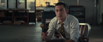 Movie still from “Inception” (2010), directed by Christopher Nolan – A man sitting on the ground wearing a tie; Medium shot, High angle