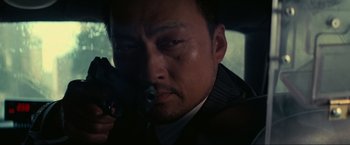 Movie still from “Inception” (2010), directed by Christopher Nolan – A person holding a gun in a car; Close Up shot, Low angle