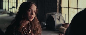 Movie still from “Inception” (2010), directed by Christopher Nolan – A woman with long brown hair sitting in a room; Close Up shot, Over the shoulder angle