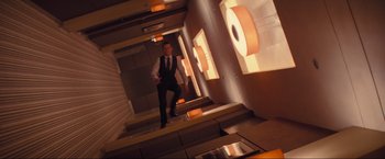 Movie still from “Inception” (2010), directed by Christopher Nolan – A man in a suit and tie walking down a flight of stairs; Wide shot, Overhead angle
