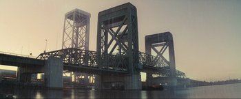 Movie still from “Inception” (2010), directed by Christopher Nolan – A large bridge that has some kind of structure on top of it; Extreme Wide shot, Low angle