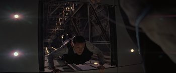 Movie still from “Inception” (2010), directed by Christopher Nolan – A man in black shirt and black vest standing in front of a mirror; Medium shot, High angle