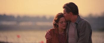 Movie still from “Inception” (2010), directed by Christopher Nolan – A man and a woman embracing each other in front of a body of water; Medium shot, Low angle
