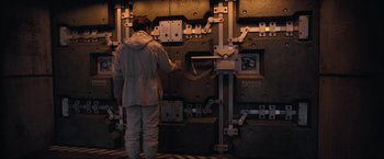 Movie still from “Inception” (2010), directed by Christopher Nolan – A man standing in front of a wall of metal; Medium shot, High angle