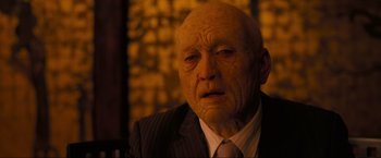 Movie still from “Inception” (2010), directed by Christopher Nolan – An old man wearing a suit and tie; Close Up shot, Over the shoulder angle