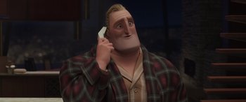 Movie still from “Incredibles 2” (2018), directed by Brad Bird – A man in a plaid jacket talking on a cell phone; Medium shot, Low angle