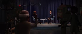 Movie still from “Incredibles 2” (2018), directed by Brad Bird – A person taking a picture of a man sitting in a chair; Wide shot, Over the shoulder angle