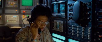 Movie still from “Independence Day” (1996), directed by Roland Emmerich – A person talking on a phone in front of a computer; Medium shot, Low angle