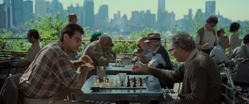 Movie still from “Independence Day” (1996), directed by Roland Emmerich – A group of people sitting at a table playing chess; Medium shot, Over the shoulder angle