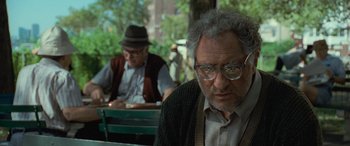 Movie still from “Independence Day” (1996), directed by Roland Emmerich – An older man sitting in front of another man at an outdoor table; Close Up shot, Over the shoulder angle