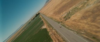 Movie still from “Independence Day” (1996), directed by Roland Emmerich – An aerial view of an empty road with a person on it; Extreme Wide shot, Overhead angle