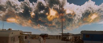 Movie still from “Independence Day” (1996), directed by Roland Emmerich – People are walking on a dirt road under a cloudy sky; Extreme Wide shot, Low angle