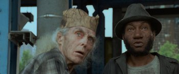 Movie still from “Independence Day” (1996), directed by Roland Emmerich – An old man wearing a paper crown next to another man; Close Up shot, Low angle