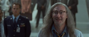 Movie still from “Independence Day” (1996), directed by Roland Emmerich – An older man with long hair and glasses smiling; Close Up shot, Low angle