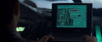 Movie still from “Independence Day” (1996), directed by Roland Emmerich – A person using a laptop computer in a dark room; Close Up shot, High angle