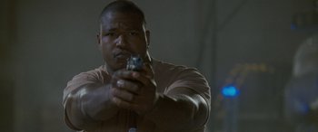 Movie still from “Independence Day” (1996), directed by Roland Emmerich – A man holding a gun in his hand; Close Up shot, Low angle