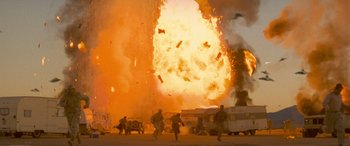Movie still from “Independence Day” (1996), directed by Roland Emmerich – People are walking in front of an explosion in a parking lot; Extreme Wide shot, Low angle