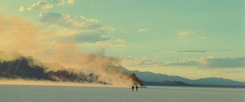 Movie still from “Independence Day” (1996), directed by Roland Emmerich – Two people walking on a beach near a large fire; Extreme Wide shot, Low angle