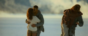 Movie still from “Independence Day” (1996), directed by Roland Emmerich – A man and a woman kissing on the beach; Wide shot, Over the shoulder angle