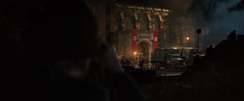 Movie still from “Indiana Jones and the Dial of Destiny” (2023), directed by James Mangold – A person taking a picture of a building with flags on it; Extreme Wide shot, High angle