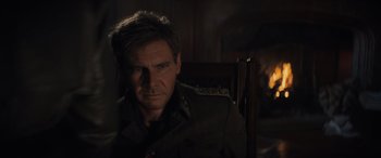 Movie still from “Indiana Jones and the Dial of Destiny” (2023), directed by James Mangold – A man sitting in a chair in a dark room; Close Up shot, Over the shoulder angle