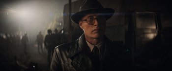 Movie still from “Indiana Jones and the Dial of Destiny” (2023), directed by James Mangold – A man wearing a hat and glasses in a dark room; Close Up shot, Low angle