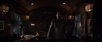 Movie still from “Indiana Jones and the Dial of Destiny” (2023), directed by James Mangold – A man in a uniform standing in front of a desk; Medium shot, Low angle