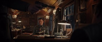Movie still from “Indiana Jones and the Dial of Destiny” (2023), directed by James Mangold – A man in a uniform sitting at a table; Medium shot, Over the shoulder angle