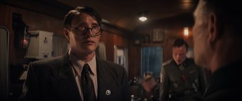 Movie still from “Indiana Jones and the Dial of Destiny” (2023), directed by James Mangold – A man in a suit and tie standing in front of a mirror; Medium shot, Low angle