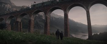 Movie still from “Indiana Jones and the Dial of Destiny” (2023), directed by James Mangold – Two people are standing on a hill looking at a train; Extreme Wide shot, Low angle