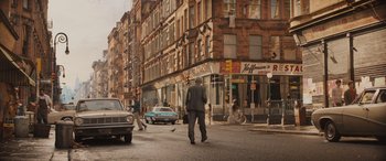 Movie still from “Indiana Jones and the Dial of Destiny” (2023), directed by James Mangold – A man in a gray suit is walking down the street; Extreme Wide shot, High angle
