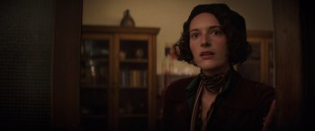 Movie still from “Indiana Jones and the Dial of Destiny” (2023), directed by James Mangold – A woman in a brown jacket standing next to a bookshelf; Close Up shot, Over the shoulder angle